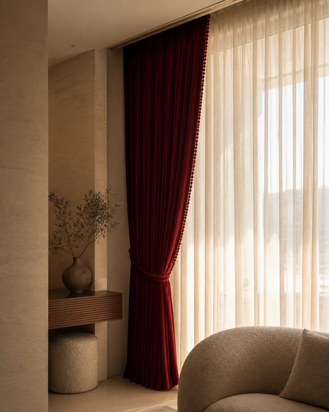Deep burgundy drapery and ivory sheers in a refined limestone interior