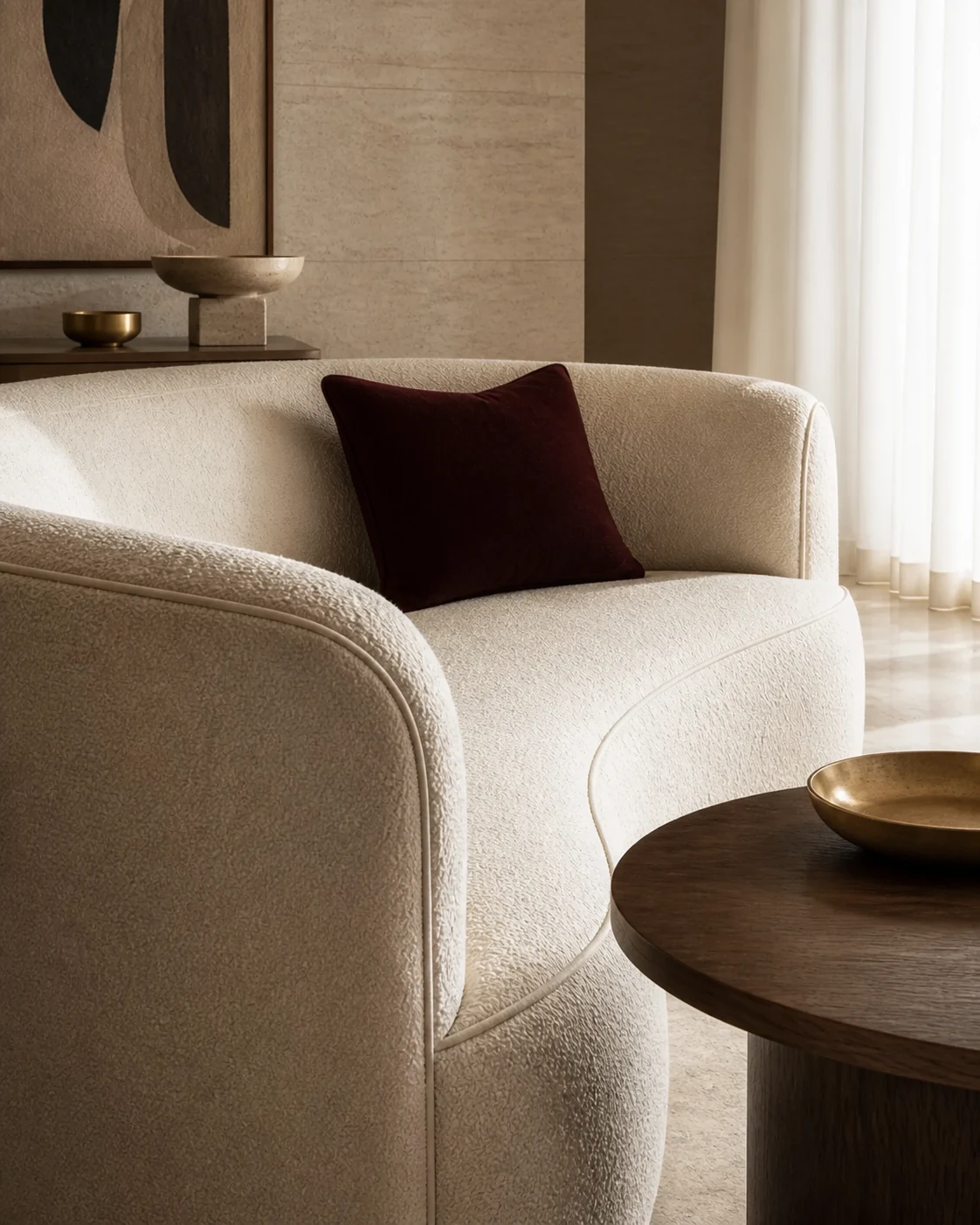 Close view of an ivory bouclé sofa with refined piping and a burgundy cushion